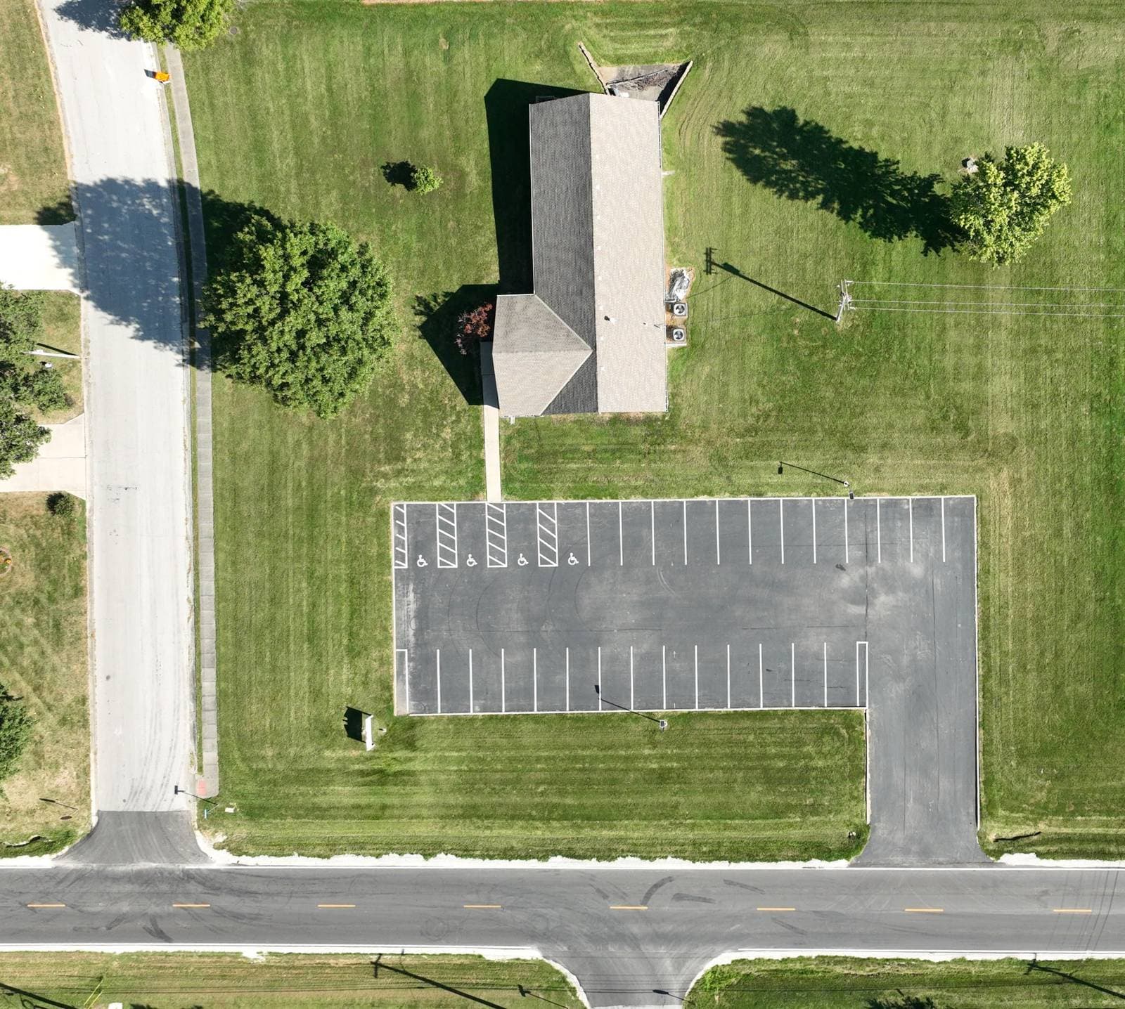 Overhead aerial photo of the church building and parking lot. Outlook Drive runs along the left side of the property and 2 Highway runs along the bottom. An arrow marks the parking lot entrance, a driveway off 2 Highway near the corner of 2 Highway and Outlook Drive.