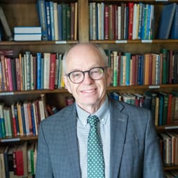 Larry Bradford wearing glasses and a green tie in front of a bookshelf